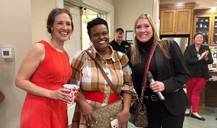 Three smiling women pose together for a photo